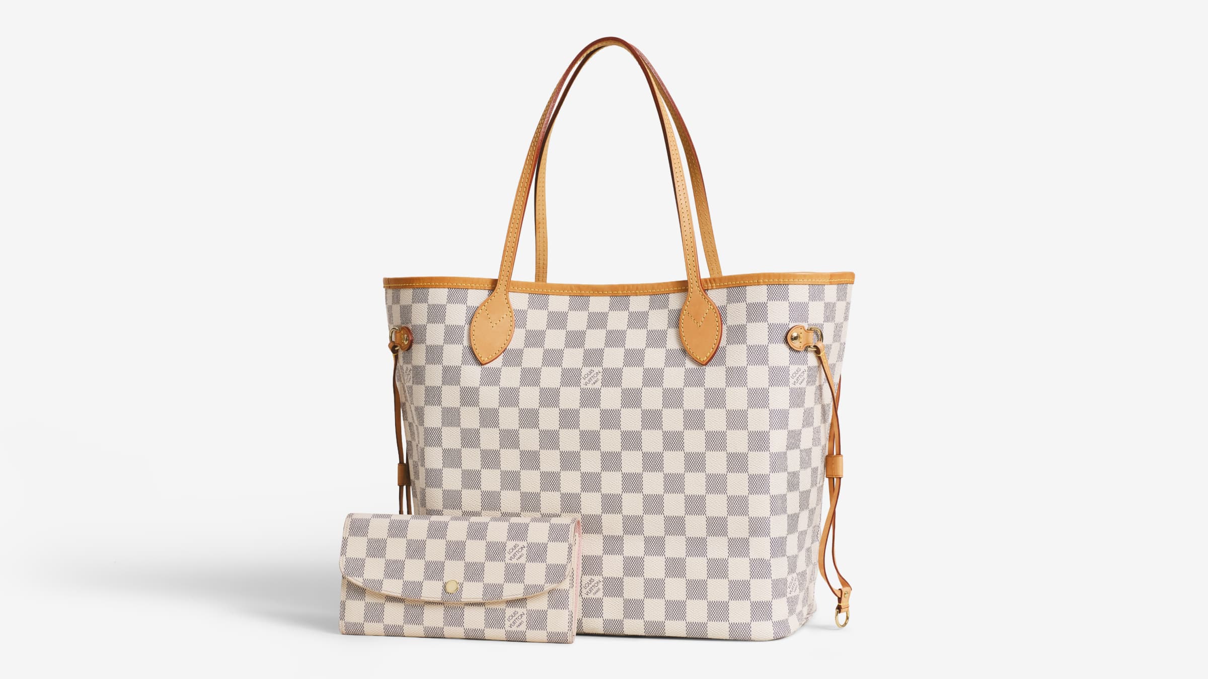 A Louis Vuitton Neverfull tote next to a Louis Vuitton Emilie Wallet