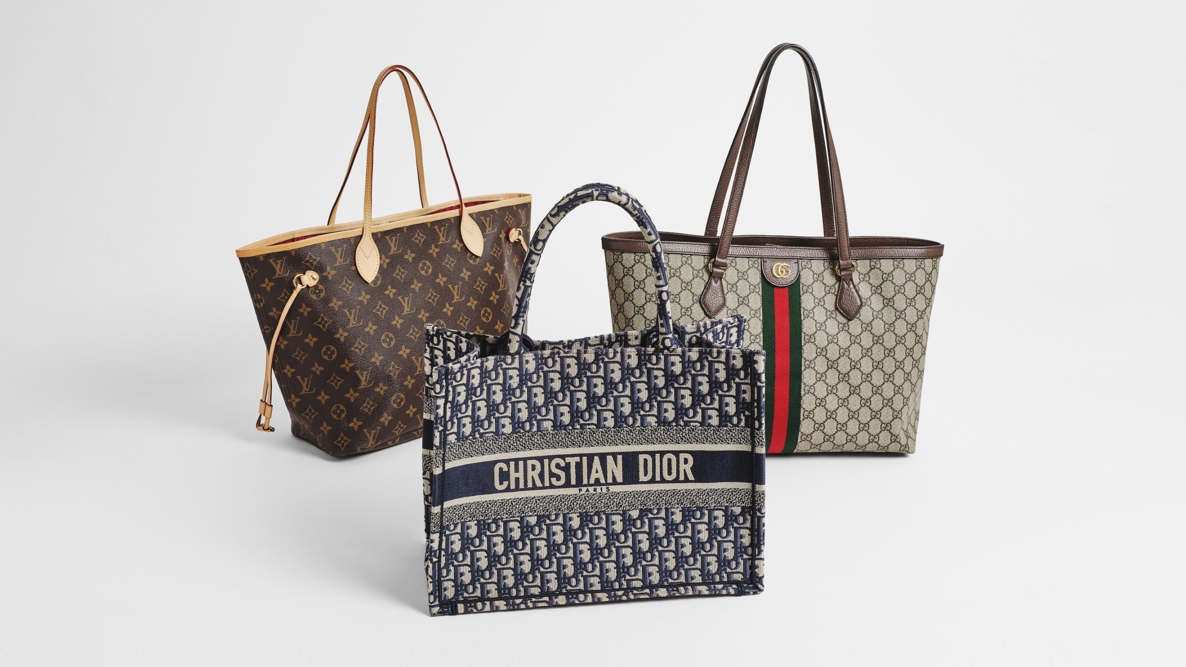 Photo of the three ultra-luxury totes centered and turned at an angle. LV Neverfull, a Christian Dior Book Tote, and a Gucci Ophidia Shopping Tote