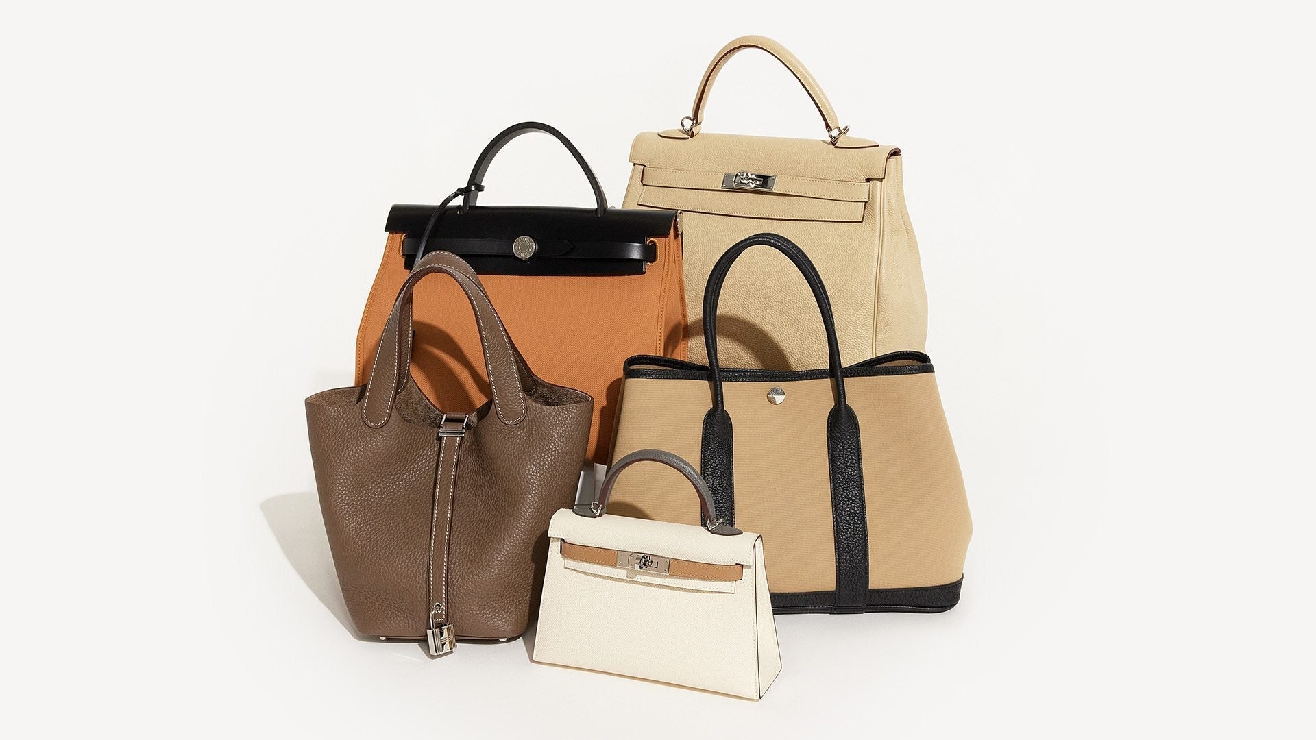 studio image of beige Hermes bags grouped together on white background FASHIONPHILE