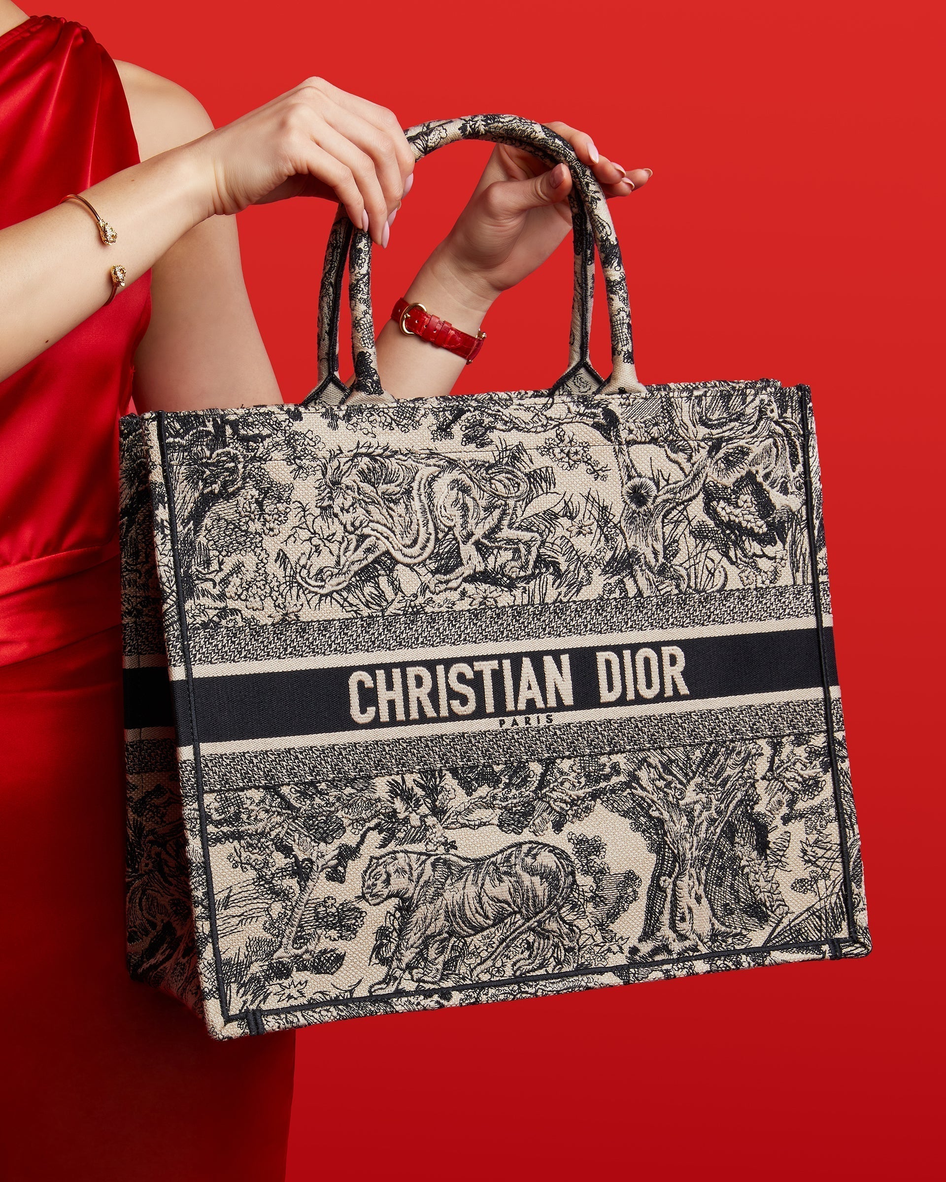 studio image of model wearing red holding Dior book tote with tiger embroidery for Lunar New Year at FASHIONPHILE