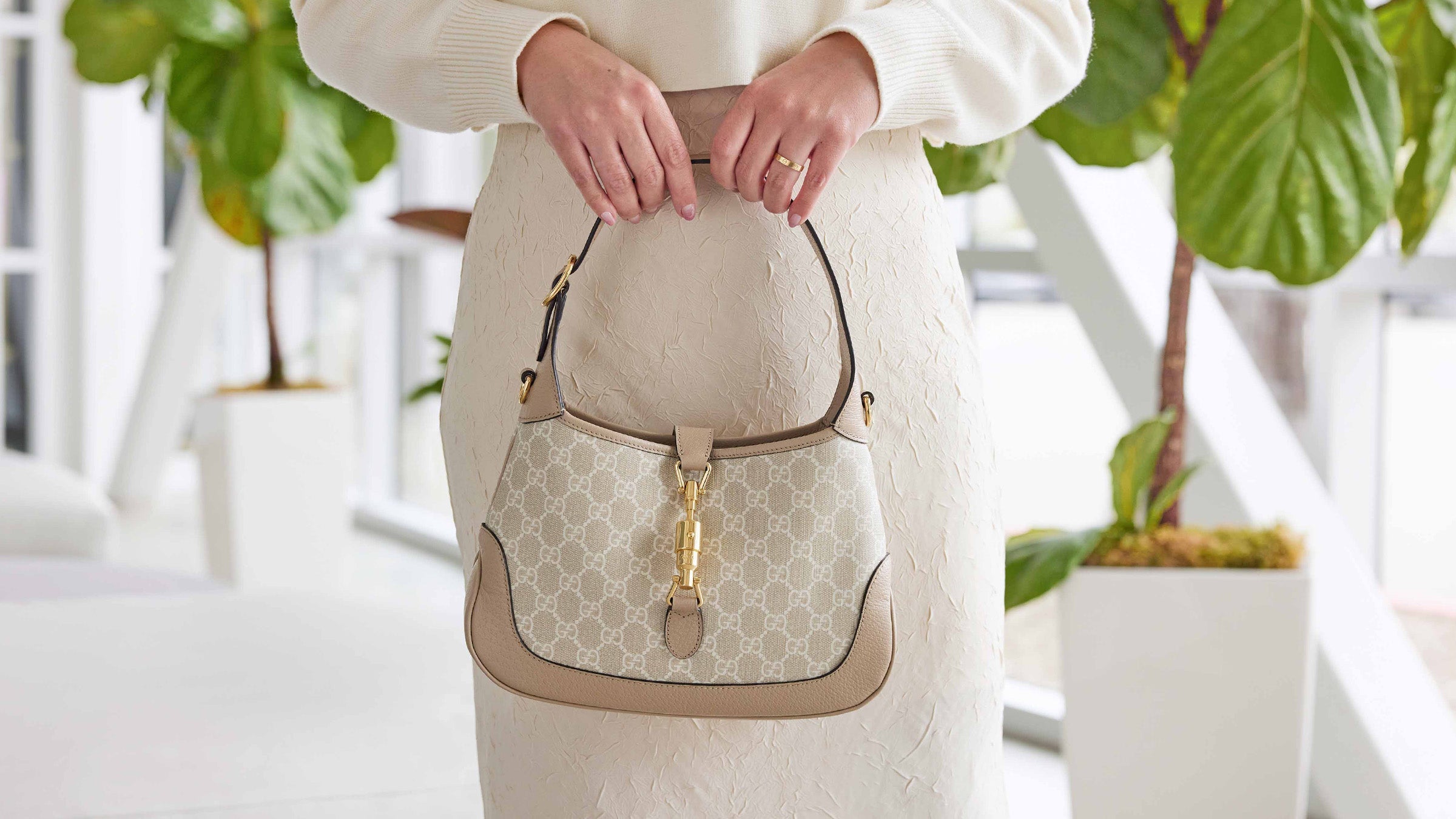 lifestyle image of model in Fashionphile showroom holdin a small gucci jackie 1961 hobo in beige