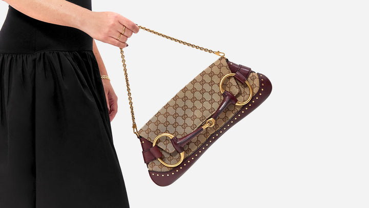 model carrying a tom ford era gucci horsebit chain clutch in the gg monogram pattern by FASHIONPHILE