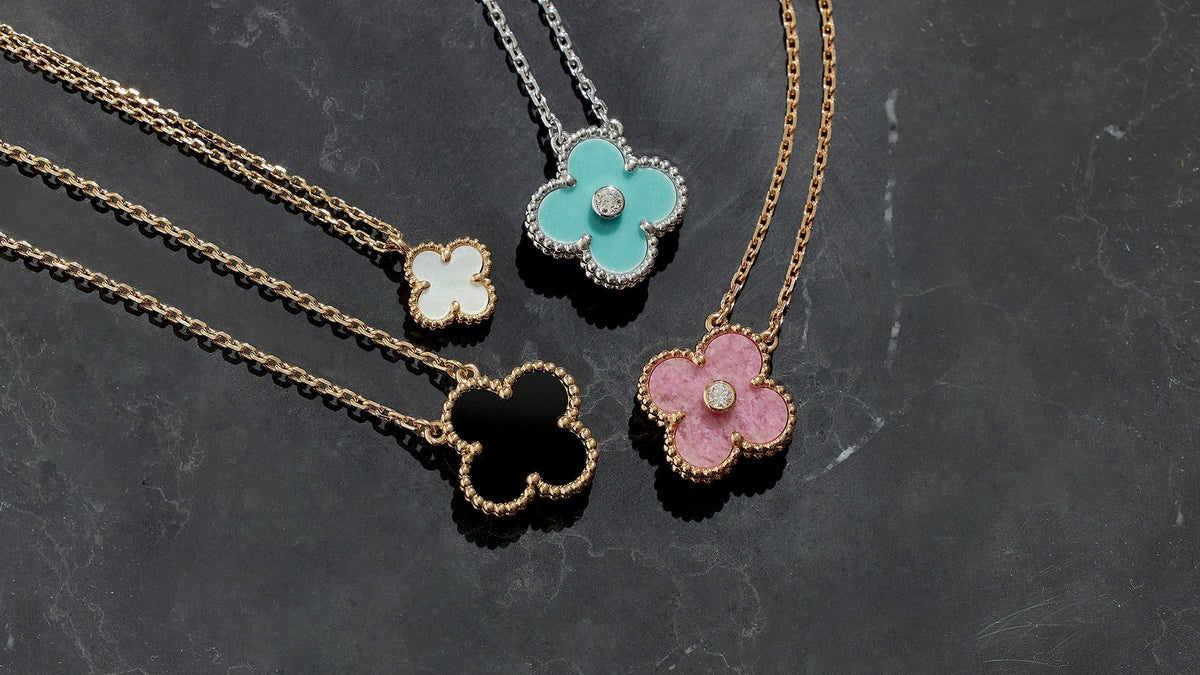 studio laydown image of van cleef & arpels alhambra pendant necklaces grouped together in various colors