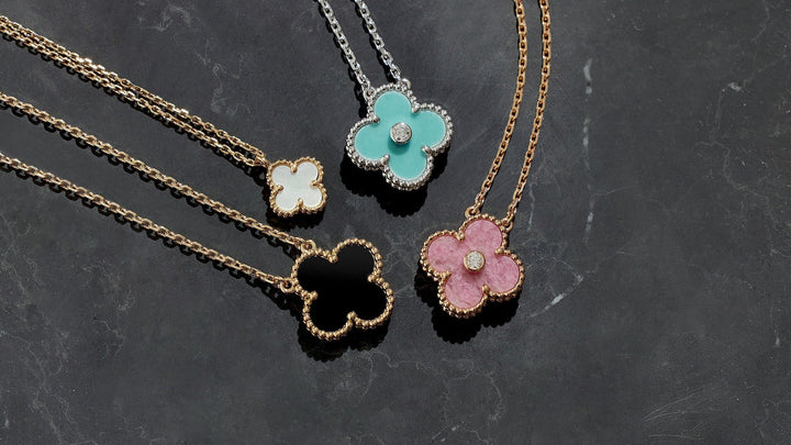 studio laydown image of van cleef & arpels alhambra pendant necklaces grouped together in various colors
