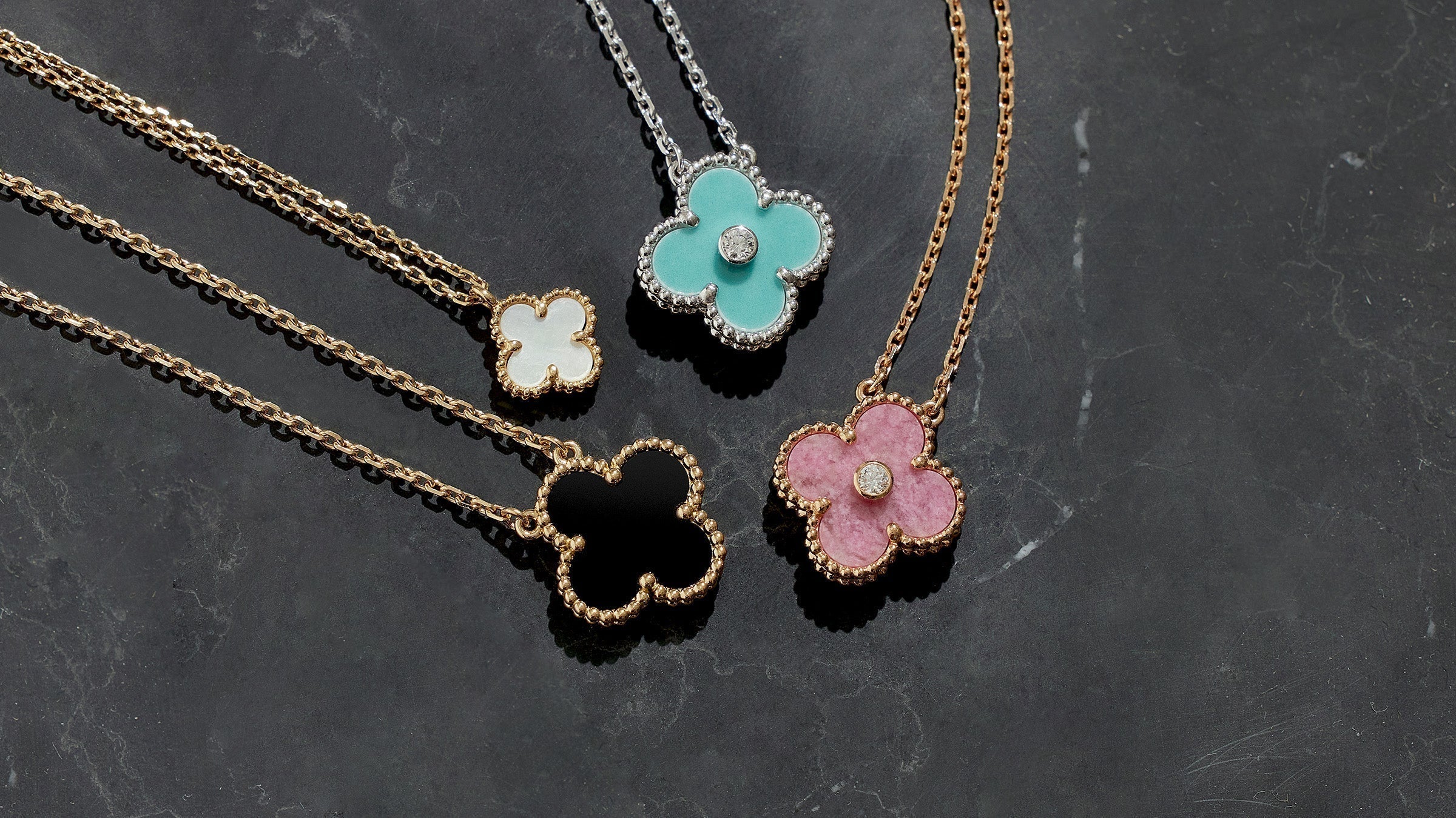 studio laydown image of van cleef & arpels alhambra pendant necklaces grouped together in various colors