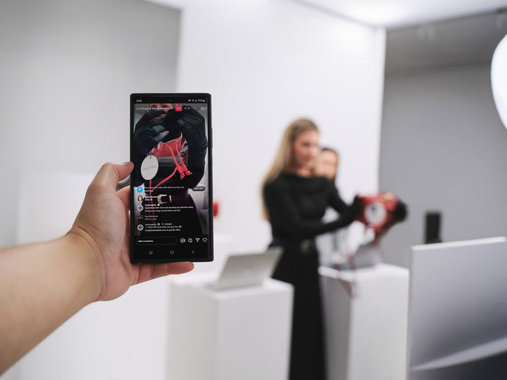Image of a hand holding a phone airing the Live Shopping with FASHIONPHILE.