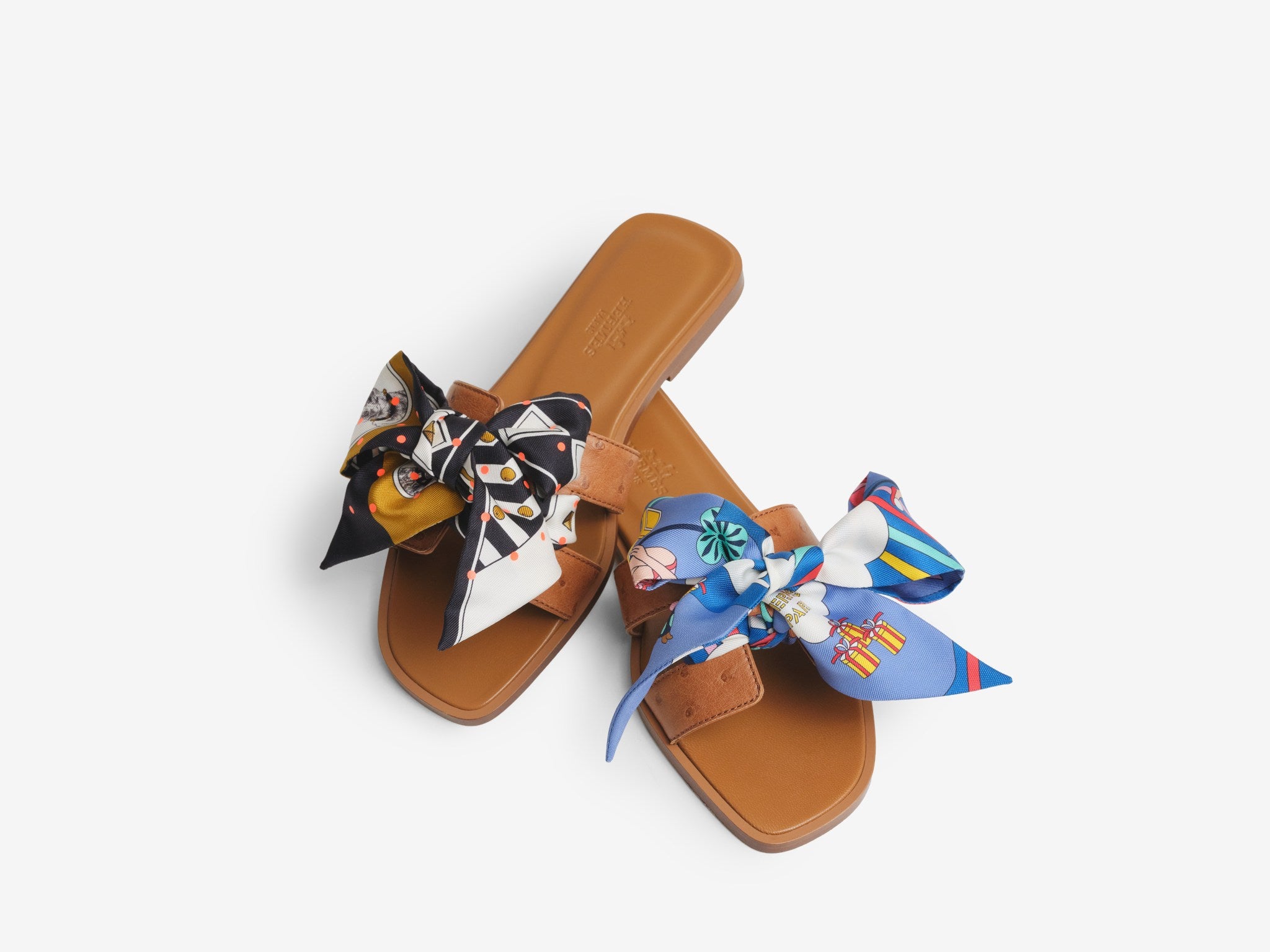 A pair or Hermes Oran sandals with a Twilly tied on the front
