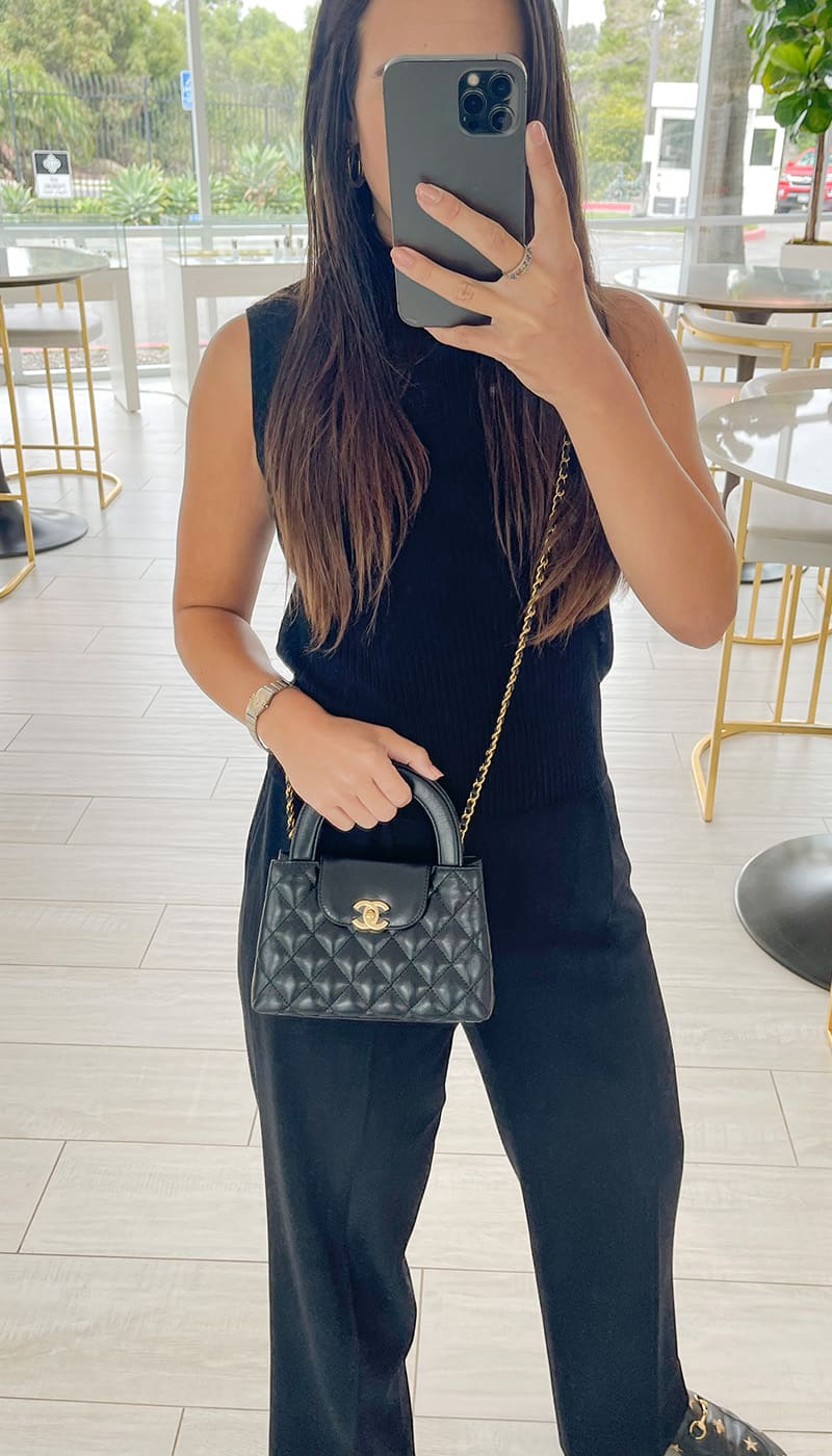 a mirror selfie image of a black chanel nano kelly shopper bag on figure inside the FASHIONPHILE Flagship in San Diego by FASHIONPHILE