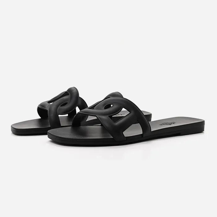 A studio image of black rubber Hermes Aloha Sandals at Fashionphile