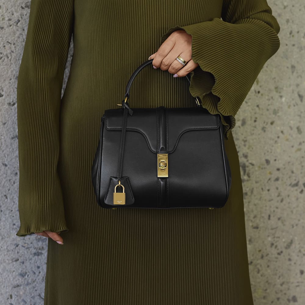 the small celine 16 bag in the color black carried as a top handle by FASHIONPHILE
