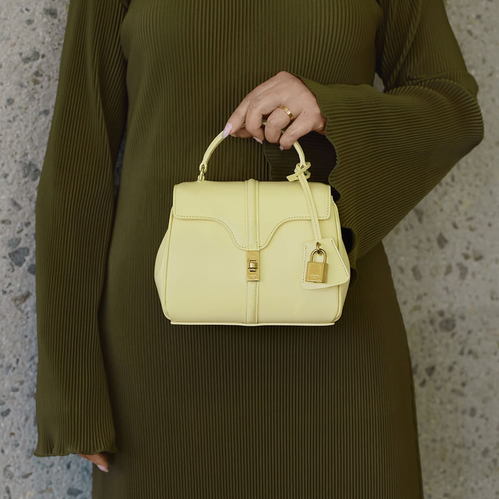 the mini celine 16 bag in the color yellow carried as a top handle by FASHIONPHILE