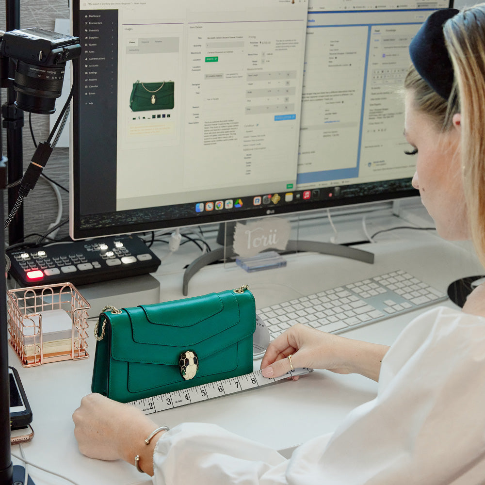 FASHIONPHILE Personal Shopper helping a customer with a question about the measurements of a green Bulgari bag
