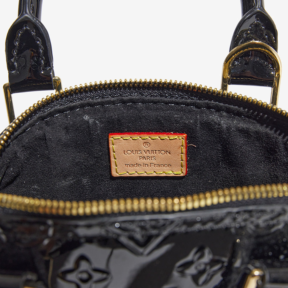 this is an image by FASHIONPHILE of a fake louis vuitton stamp inside a vernis louis vuitton alma bb bag