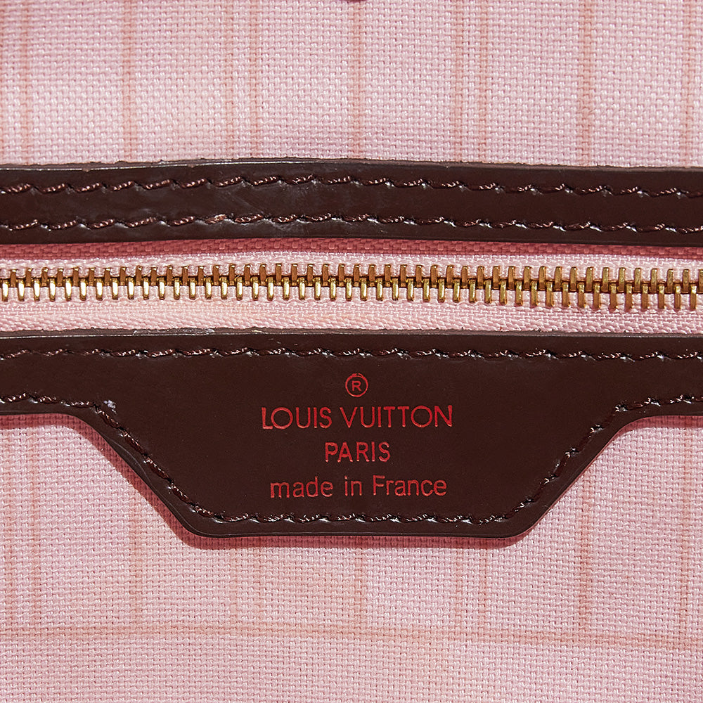 this is a close up image of a fake interior logo stamp on a damier ebene louis vuitton neverfull bag by fashionphile