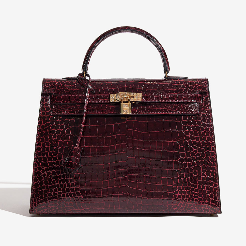 this is an image of an HERMES Shiny Porosus Crocodile 18K Rose Gold Diamond Kelly Sellier 35 in the color Bordeaux by FASHIONPHILE