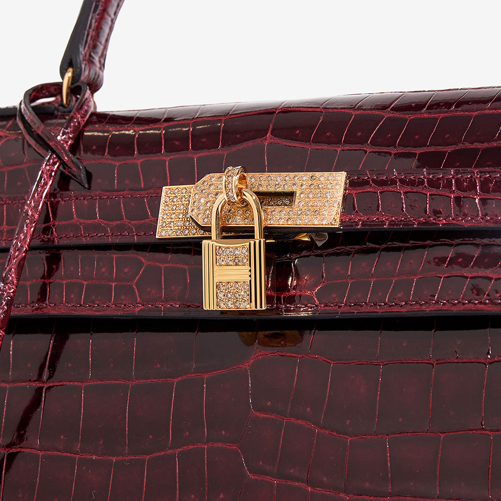 close up image of an HERMES Shiny Porosus Crocodile 18K Rose Gold Diamond Kelly Sellier 35 in the color Bordeaux by FASHIONPHILE