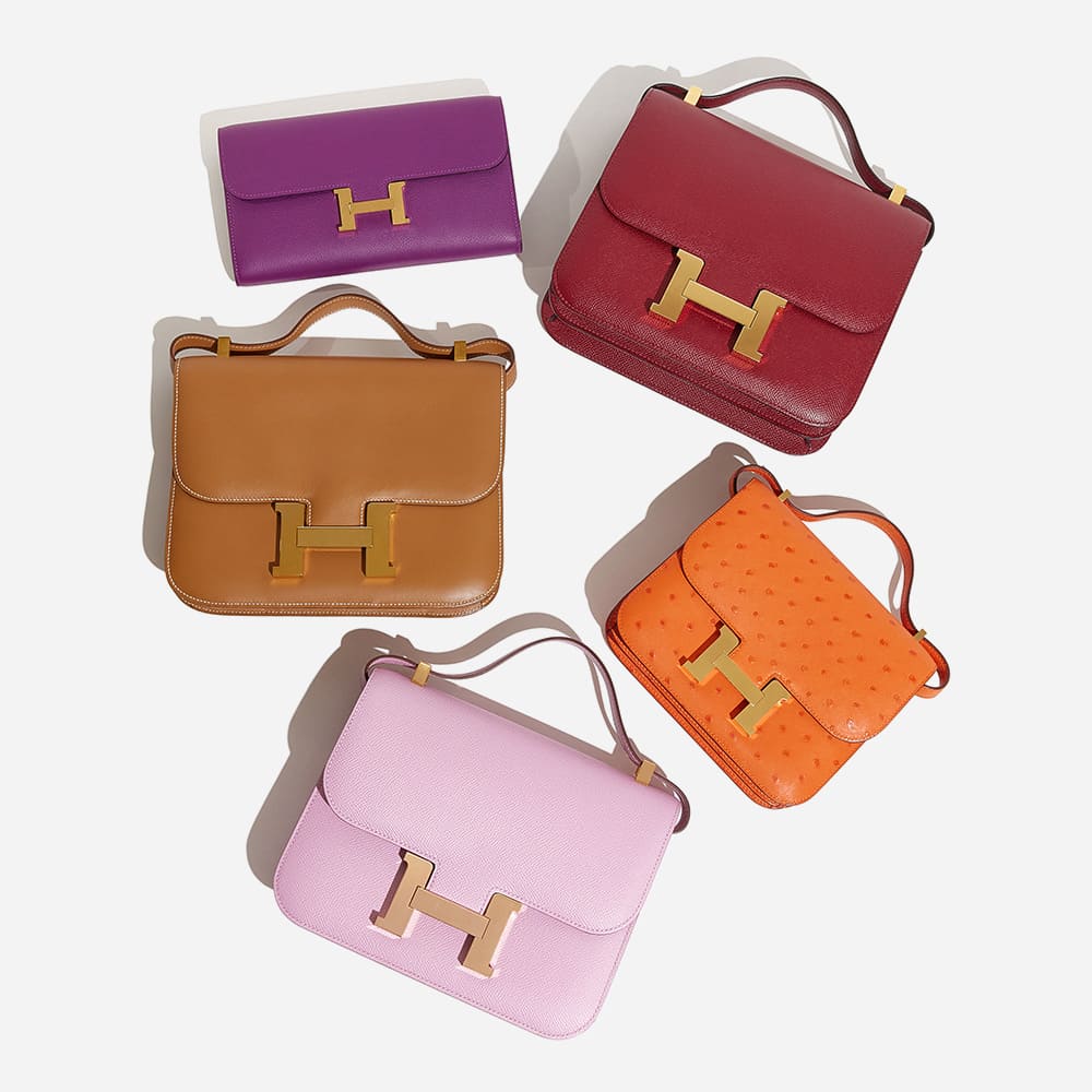 a laydown of different colored hermes constance bag styles by FASHIONPHILE