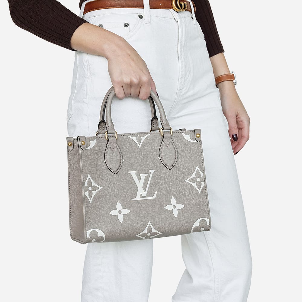 a beige leather giant monogram louis vuitton onthego tote in size pm worn as a top handle bag by FASHIONPHILE