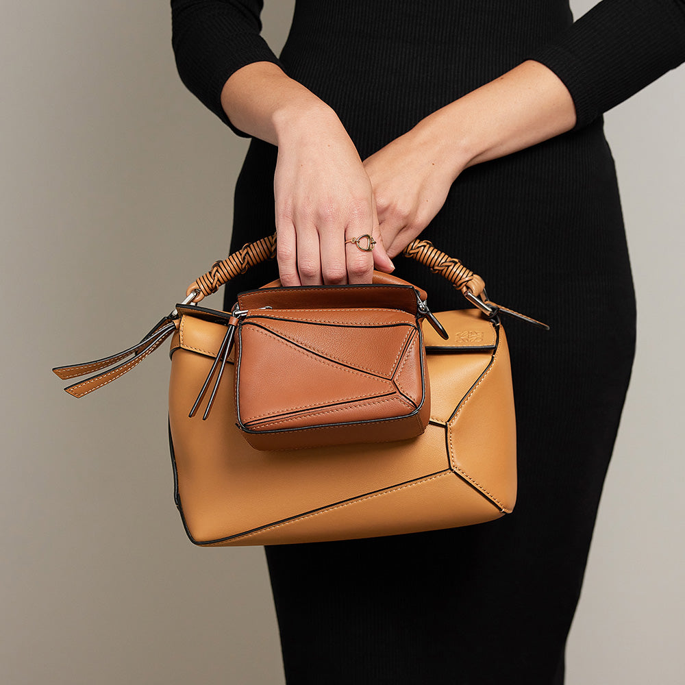 Model holding Puzzle bags comparing the Nano Puzzle bag size with the Small Puzzle Bag size by fashionphile