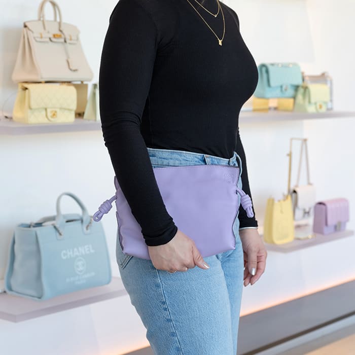 image of shopper holding the loewe flamenco clutch in lavender purple inside the FASHIONPHILE San Diego Flagship
