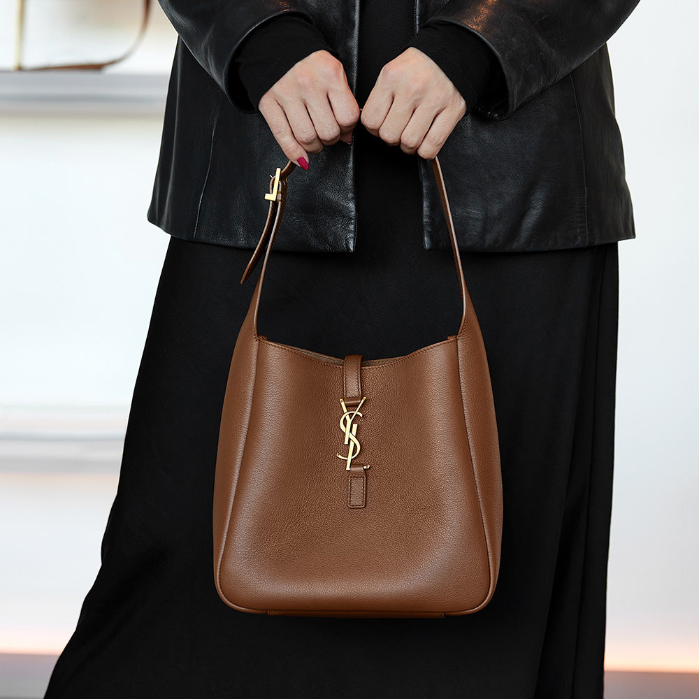 the saint laurent soft hobo bag in brown held by the hands by FASHIONPHILE