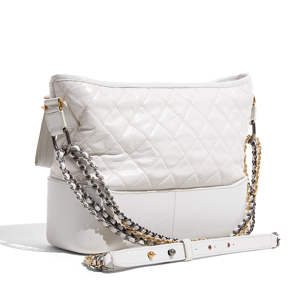 this is a side view image of a fake white chanel gabrielle hobo bag by fashionphile