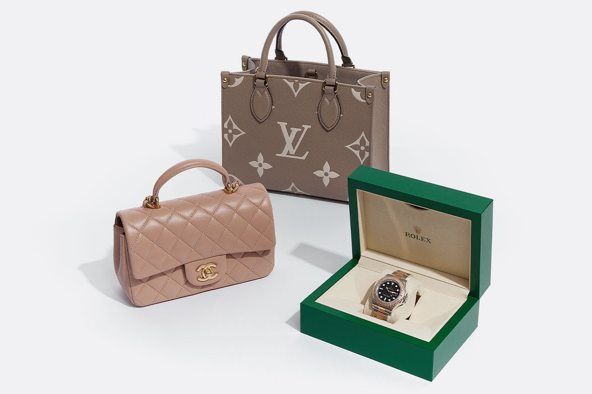 one beige Chanel top handle rectangular flap bag, one grey Louis Vuitton Giant Mongram Onthego Tote bag, and one Rolex watch sitting in it's green Rolex case