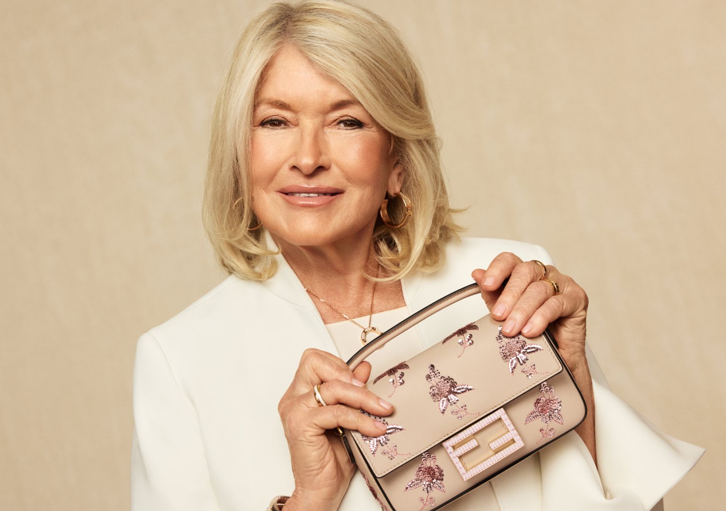 Martha Stewart in a white suit holding a FENDI Vitello Grace Sequin Embroidered Flower Bouquet Mini Baguette Soap