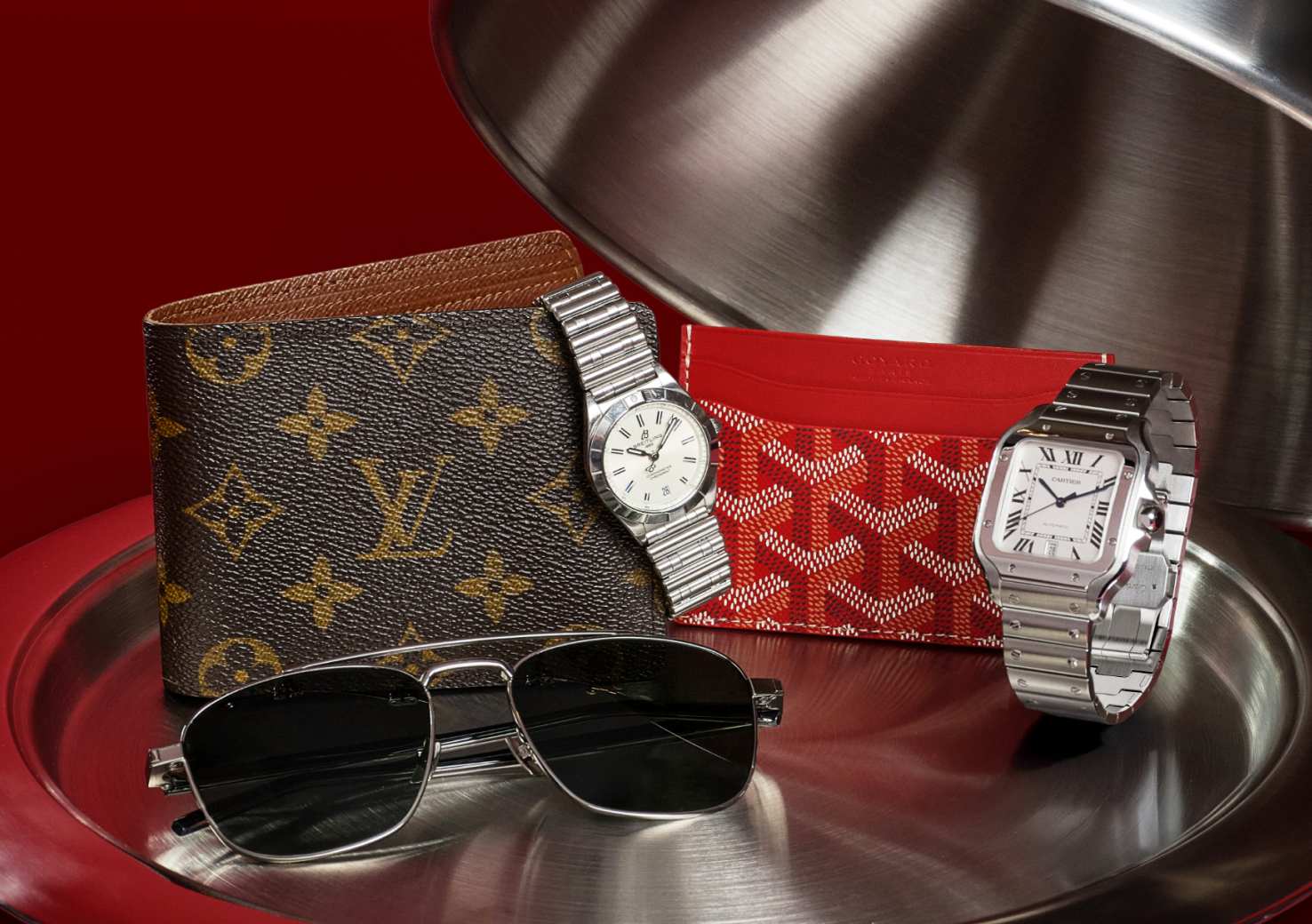 one Louis Vuitton Monogram Multiple Wallet, one Goyard Goyardine Saint Sulpice Card Holder Red, one pair of Saint Laurent Acetate Metal Aviator Sunglasses Black, on Cartier Stainless Steel 39.8mm Santos De Cartier Automatic Watch, and one Breitling Stainless Steel 32mm Chronomat Quartz Watch White sitting on a serving tray