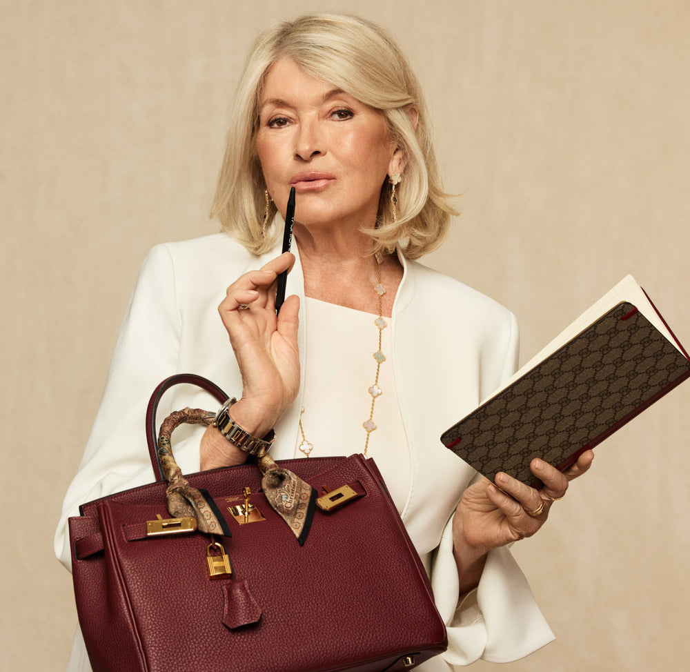 Martha Stewart in a white suit holding a red Birkin and a Gucci monogram planner