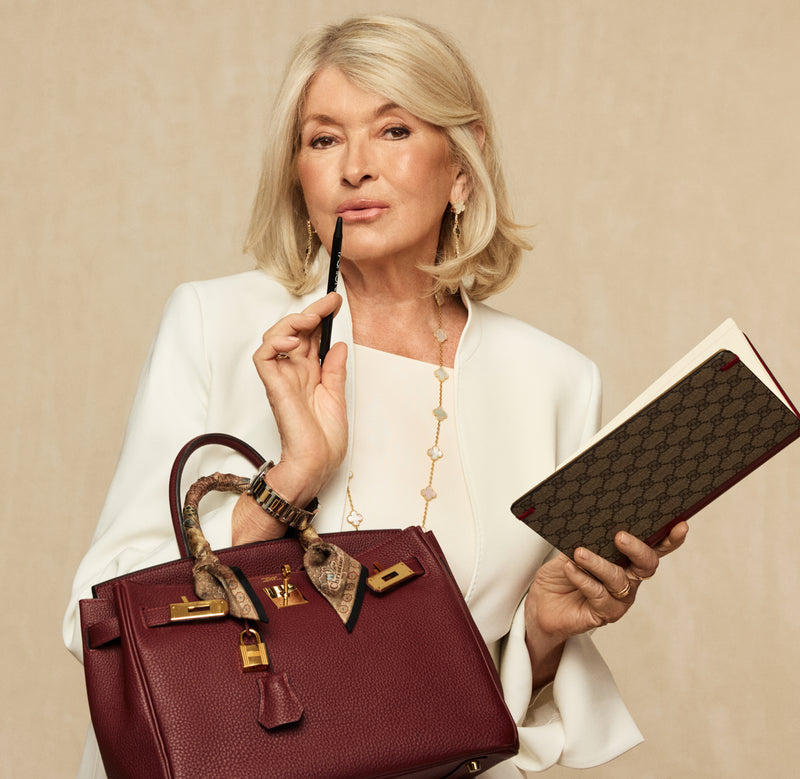 Martha Stewart in a white suit holding a red Birkin and a Gucci monogram planner