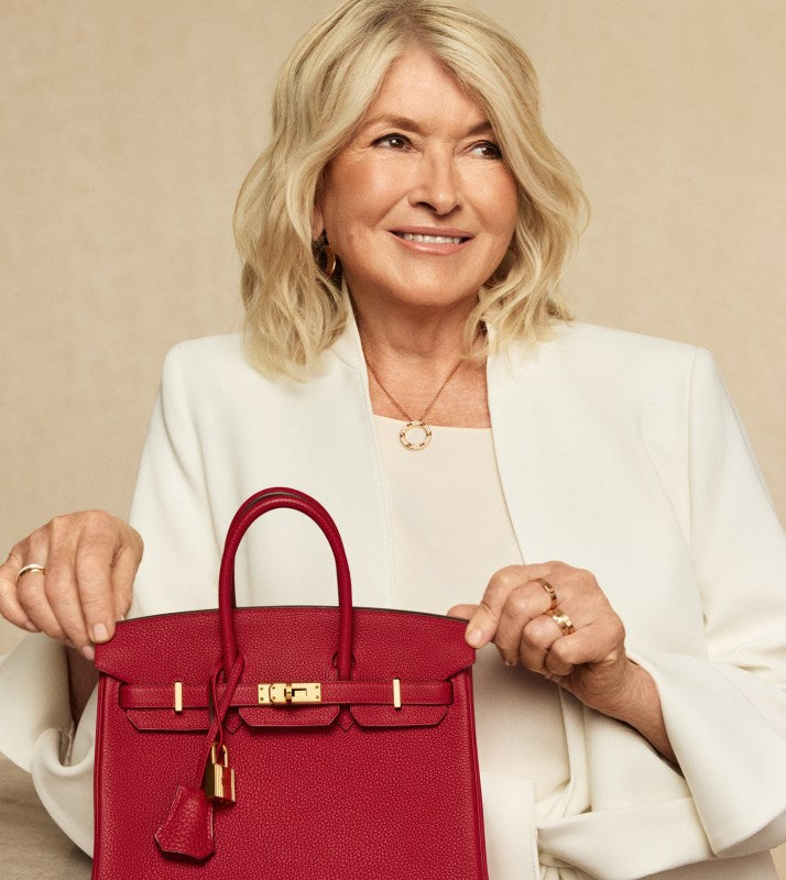 Martha Stewart in a white suit holding a red Hermes Birkin