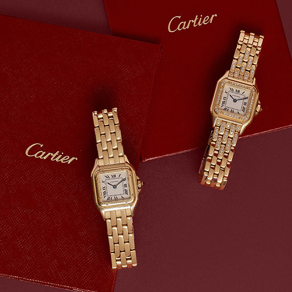 one yellow gold Cartier Panthere watch and one yellow gold Cartier Panthere watch with diamonds around the bezel both sitting on red Cartier certificates on a burgundy background
