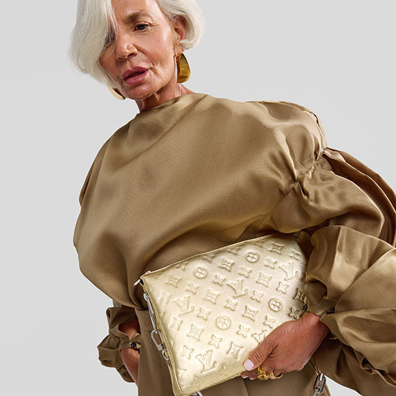 Grece Ghanem wearing a satin olive green color blouse with puff sleeves and holding a gold metallic Louis Vuitton monogram embossed Capucines bag
