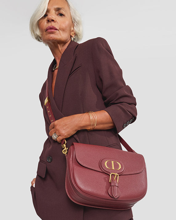 Grece Ghanem wearing a burgundy suit and a burgundy Christian Dior Grained Calfskin Large Bobby Flap bag crossbody