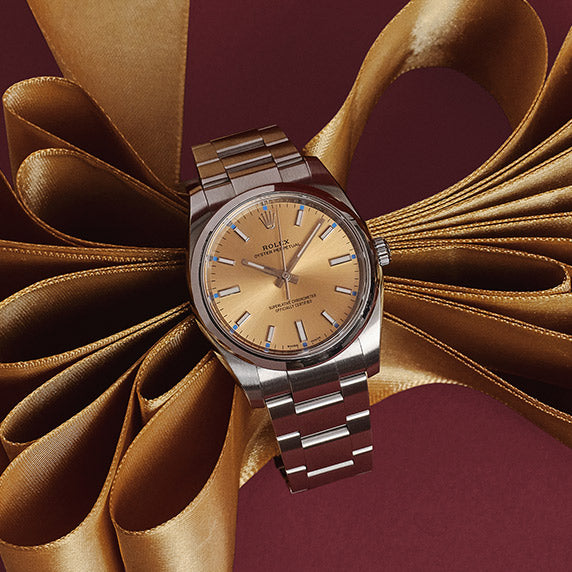 a Rolex Stainless Steel 34mm Oyster Perpetual Watch with a Champagne color face with gold satin ribbon layered inside the band