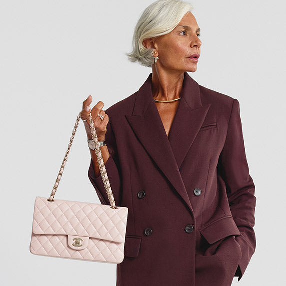 Grece Ghanem wearing a burgundy suit and holding a light pink Chanel quilted Double flap bag with gold tone hardware