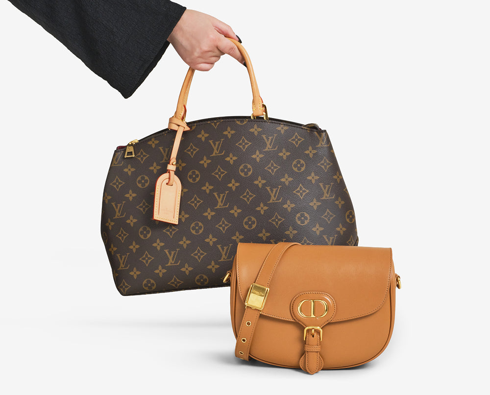 a woman's arm holding a Louis Vuitton monogram tote bag behind a Christian Dior tan Caro crossbody bag