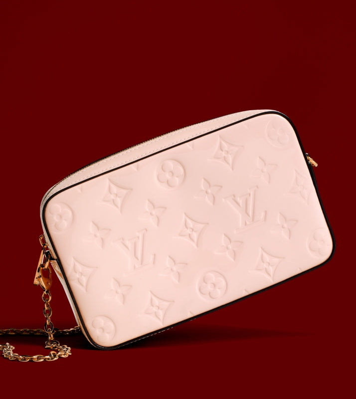 one LOUIS VUITTON Vernis Camera Pouch Rose Ballerine on a red background