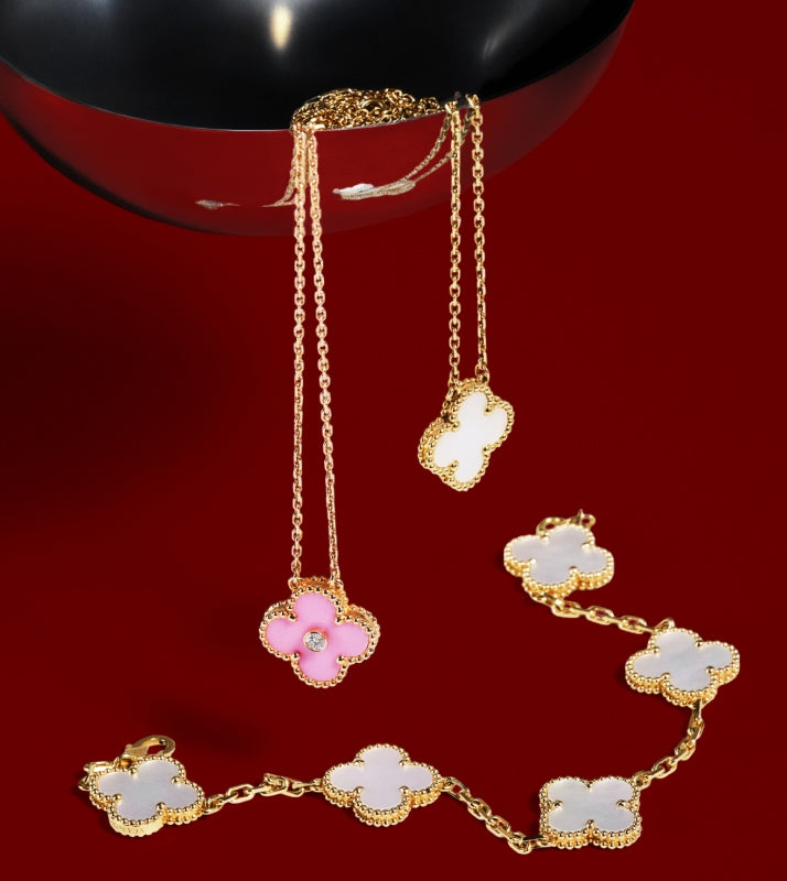 Two Van Cleef Alhambra necklaces spilling out of a serving spoon onto a Van Cleef Alhambra bracelet