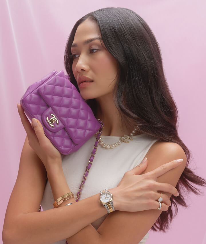 a woman wearing a white sleeveless top and holding a purple Chanel square flap bag