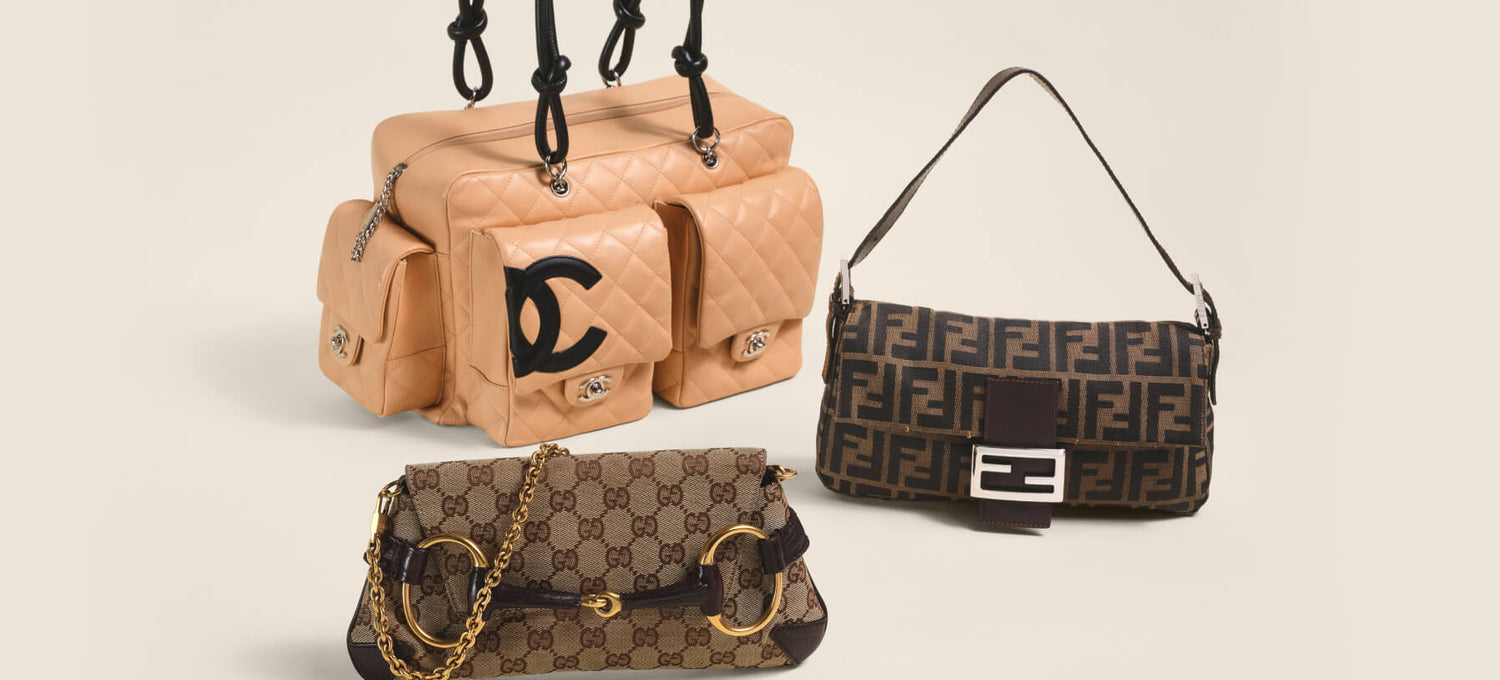 Three designer handbags displayed against a light beige background: a tan quilted Chanel shoulder bag with black handles, a brown and beige Gucci monogram shoulder bag with gold chain and hardware, and a dark brown Fendi monogram shoulder bag with a black strap.