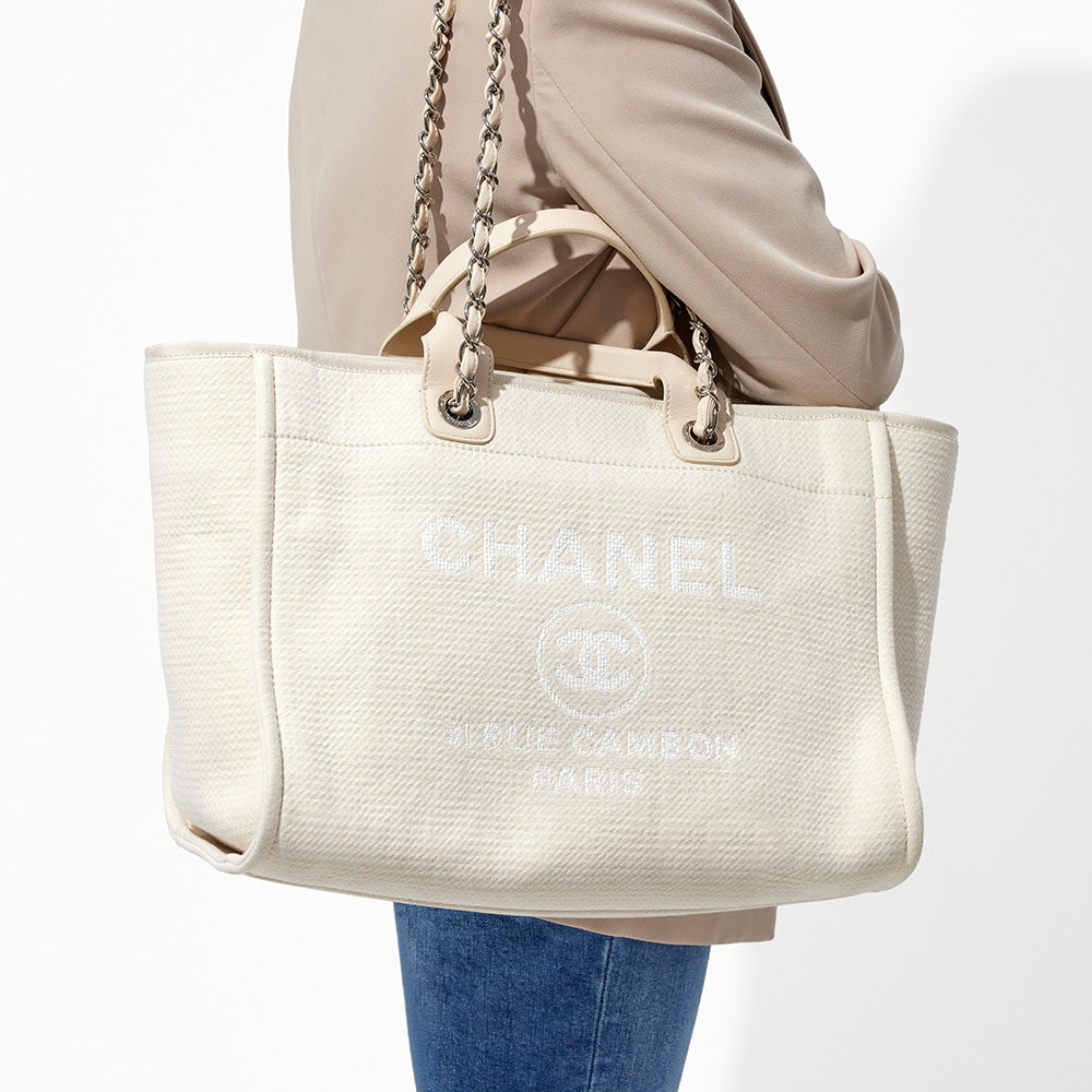 this is an image by FASHIONPHILE of a model wearing a white medium chanel deauville tote on her shoulder