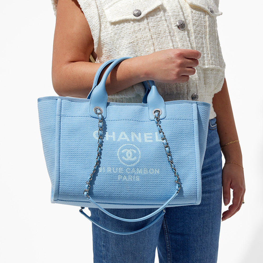 this is an image by FASHIONPHILE of a model holding a light blue new small chanel deauville tote on her arm