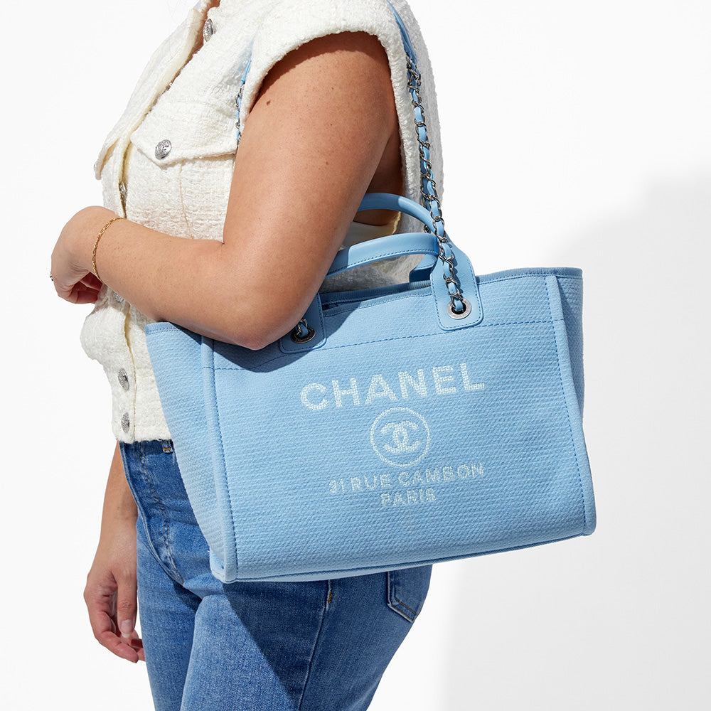 this is an image by FASHIONPHILE of a model wearing a light blue new small chanel deauville tote on her shoulder