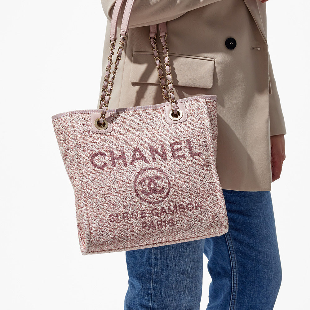 this is an image by FASHIONPHILE of a model wearing a pink mini chanel deauville tote on her arm